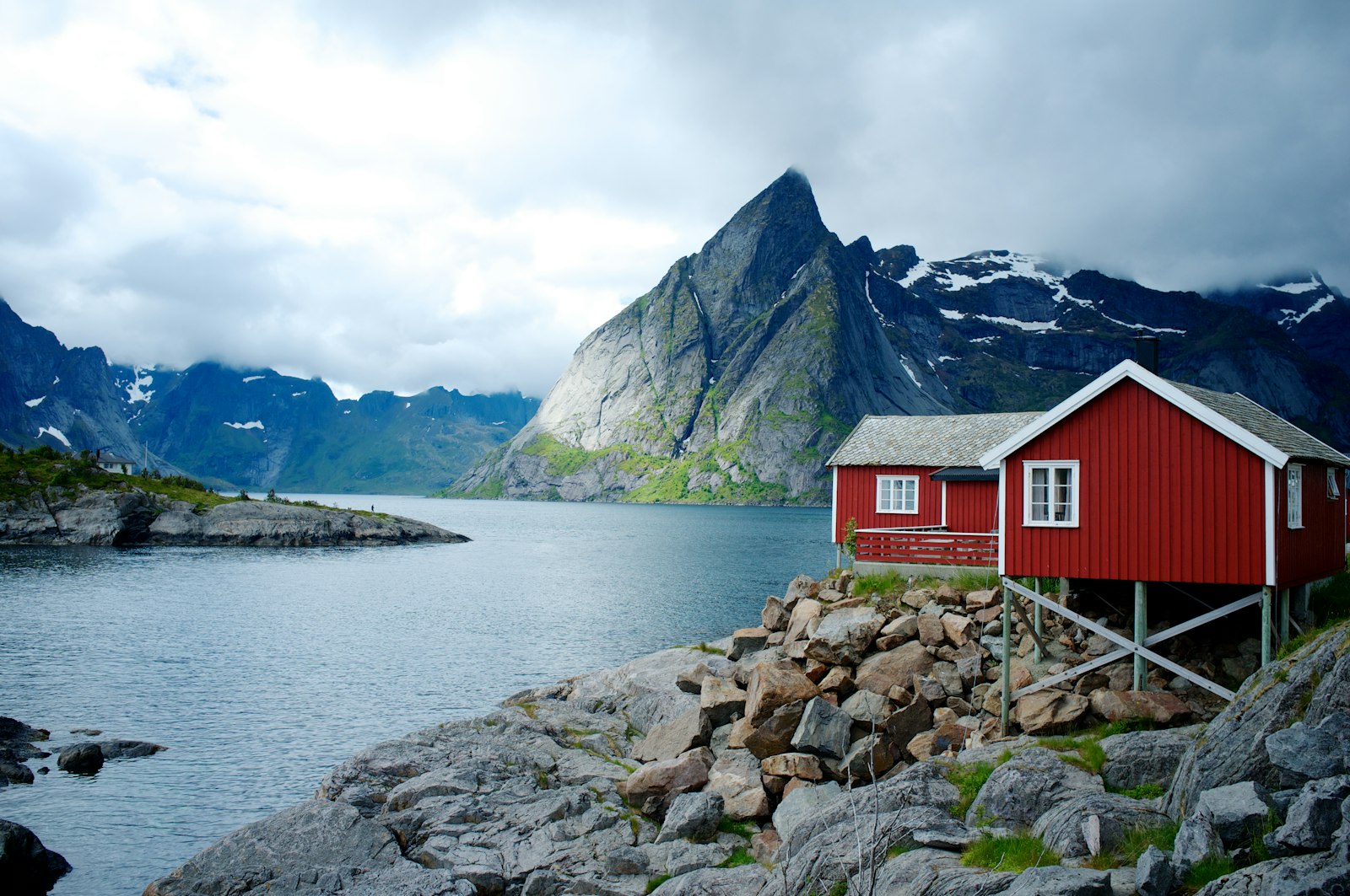 Hytte ved fjorden med bratte fjell bak